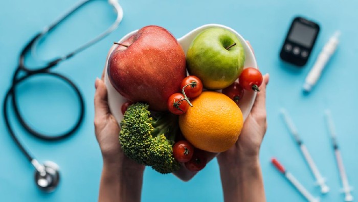 fruits and vegetables in female hands with medical equipment on blue background
