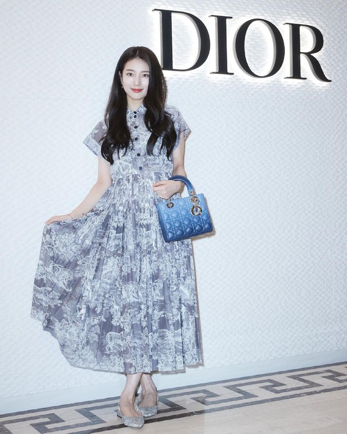Di kesempatan ini, Suzy hadir mengenakan pakaian lengkap bermerek Dior. Mulai dari Dioriviera Mid-Length Dress, Lady Dior My ABCDior Bag, flat shoes J’adior Slingback Ballerina, serta aksesoris gelang dan anting dari Dior. (Foto: Instagram.com/voguekorea)