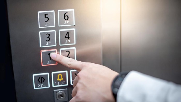 Male forefinger (index finger) pressing on the first floor button or floor number one in elevator (lift). Mechanical engineering concept