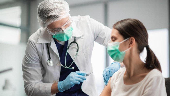 The covid-19 vaccine is injected into a young woman's hand.