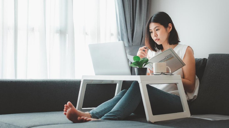 Asian woman working with laptop notebook at home on sofa