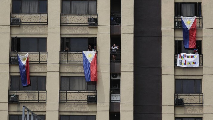 Virus Outbreak Philippines Residents display Philippine flags from their windows as they pay tribute to health workers, essential personnel and security forces during an enhanced community quarantine to prevent the spread of the new coronavirus in Manila, Philippines, Sunday, April 12, 2020. The new coronavirus causes mild or moderate symptoms for most people, but for some, especially older adults and people with existing health problems, it can cause more severe illness or death. (AP Photo/Aaron Favila)