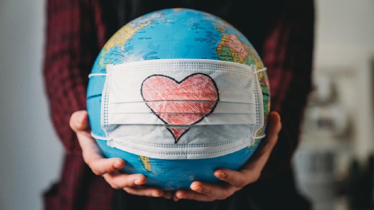Ilustrasi Perubahan Iklim Young woman holding a globe with a face mask on it - Conceptual Coronavirus Covid-19 virus pandemic - Heart shape is drawn on the mask.