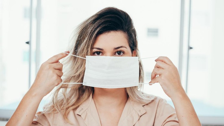 Portrait of woman wearing surgical mask at home. Covid-19, coronavirus and quarantine concept.