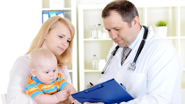Smiling pediatrician examining a cute little girl at her office.
