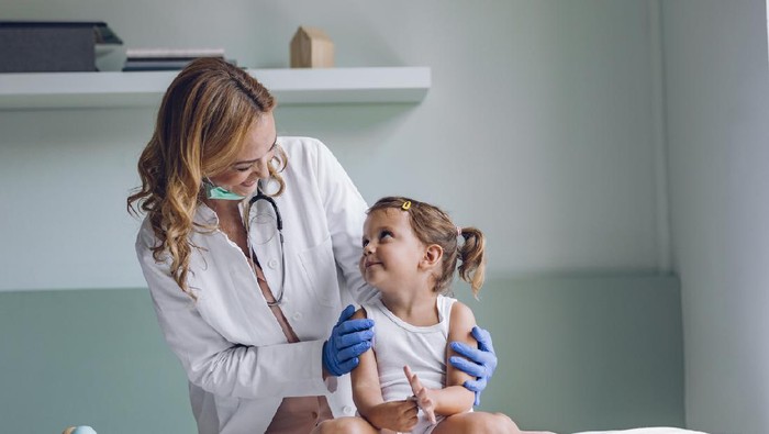 Smiling pediatrician examining a cute little girl at her office.