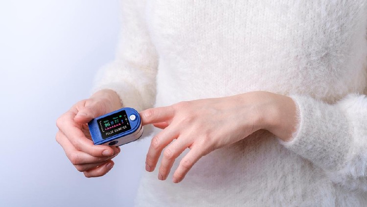 Person using pulse oximeter device on finger, healthcare monitoring concept