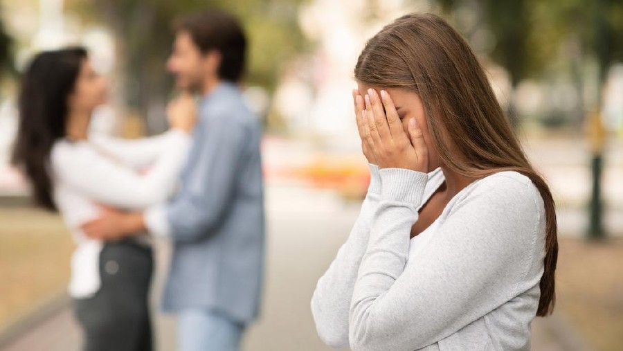 Upset woman crying, seeing her boyfriend with other girl in park