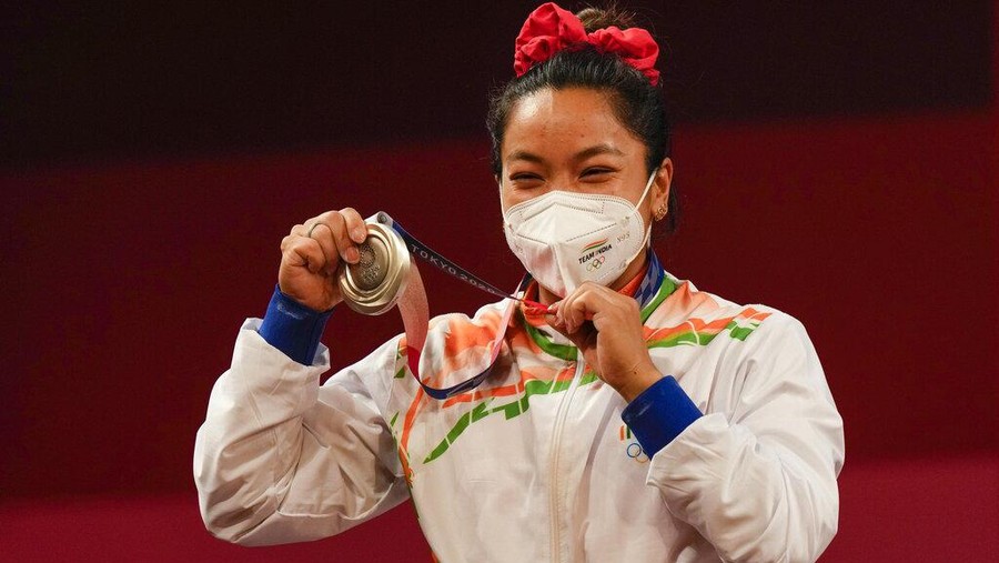 Chanu Saikhom Mirabai of India celebrates on the podium after winning the silver medal in the women's 49kg weightlifting event, at the 2020 Summer Olympics, Saturday, July 24, 2021, in Tokyo, Japan. (AP Photo/Luca Bruno)