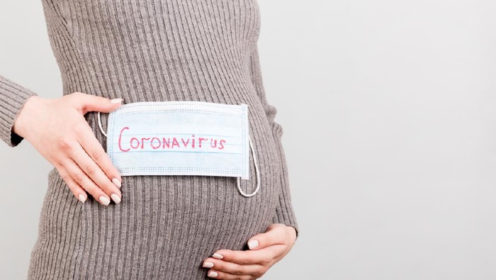 Worried pregnant woman with protective face mask on sofa at home. sick pregnant woman during COVID-19.