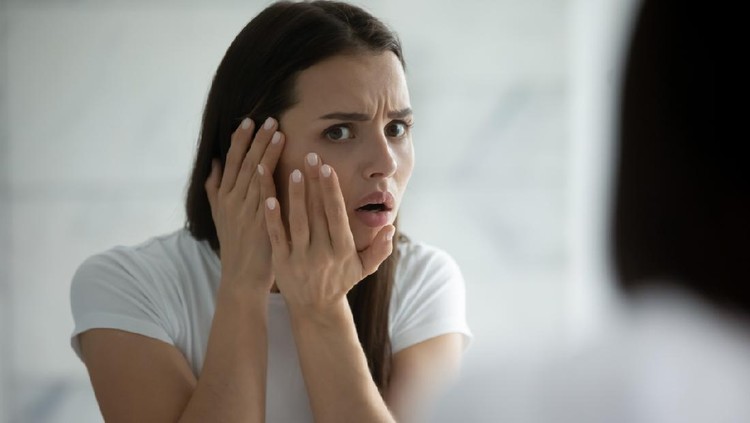 Oh god, a pimple! Anxious worried girl teenager or millennial woman watching herself in big mirror troubled by bad condition of facial skin acne wrinkles freckles sunspots oily irritated problem skin