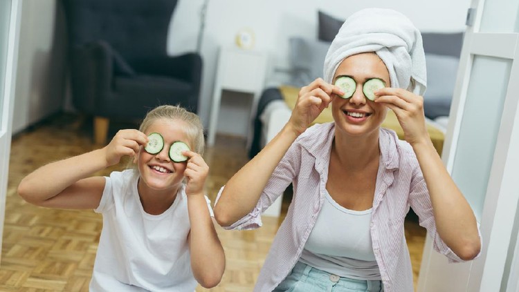 mother and daughter applying cosmetic face mask at home