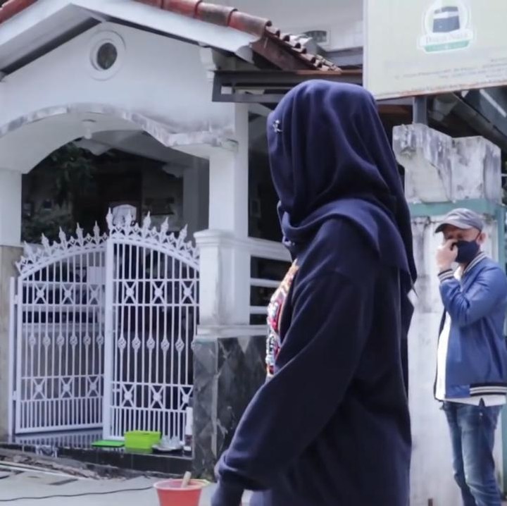 <p>Setelah melewati gang, sampailah Desy di rumah orang tuanya, Bunda. Rumah masa kecil Desy memiliki pagar putih yang masih sama seperti dahulu. (Foto: YouTube Desy Ratnasari)</p>
