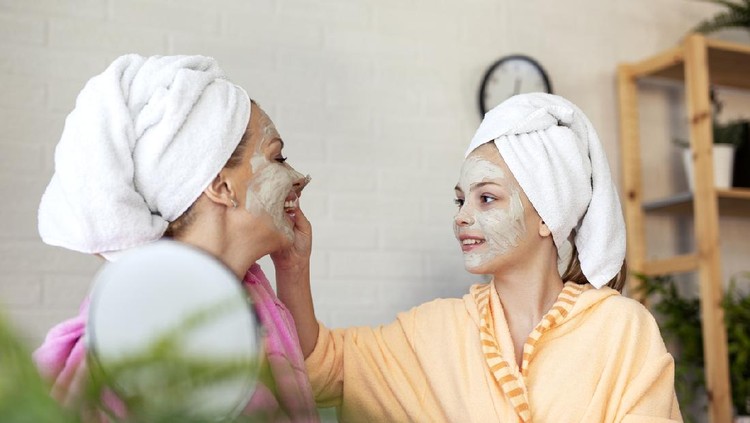 Mother and her daughter put natural musk on face for better skin and towels on head