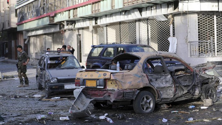 An Afghan national army soldier, left, stands guard near debris following an attack in Kabul, Afghanistan, Wednesday, Aug. 4, 2021. A powerful explosion rocked an upscale neighborhood of Afghanistan's capital Tuesday in an attack that apparently targeted the country's acting defense minister. (AP Photo/Rahmat Gul)