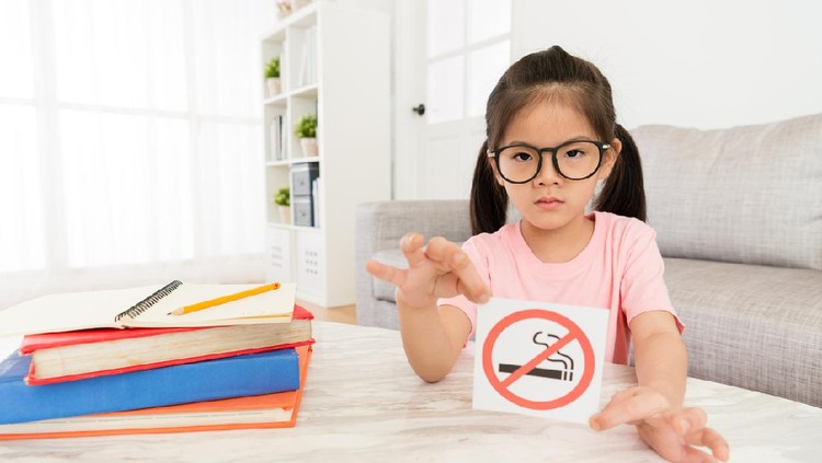 beauty elegant girl kid showing no smoking sign to camera when she doing school studying homework in living room at home.