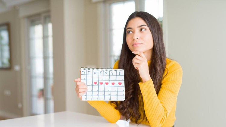 Young woman holding menstruation calendar serious face thinking about question, very confused idea