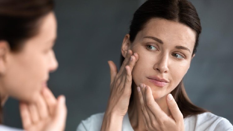 Ilustrasi Kulit Kering Close up unhappy sad woman looking at red acne spots on chin in mirror, upset young female dissatisfied by unhealthy skin, touching, checking dry irritated face skin, skincare and treatment concept