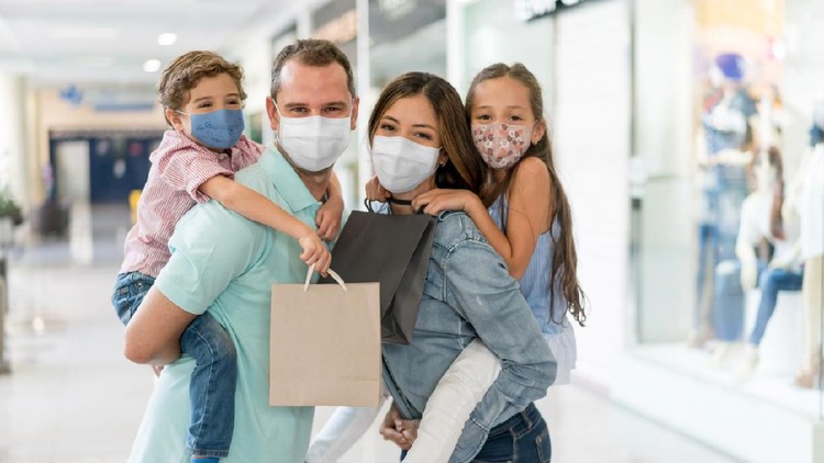 Ilustrasi orang tua ajak anak ke mal Portrait of a happy Latin American family shopping at the mall wearing facemasks during the COVID-19 pandemic – reopening of businesses concepts