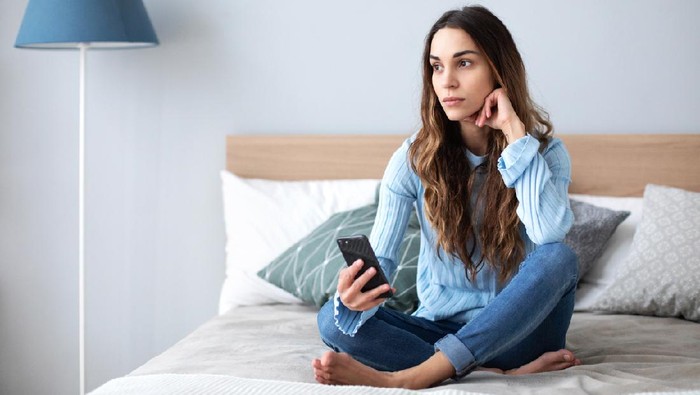 Upset woman with smart phone at home on the sofa. Stressed lady.