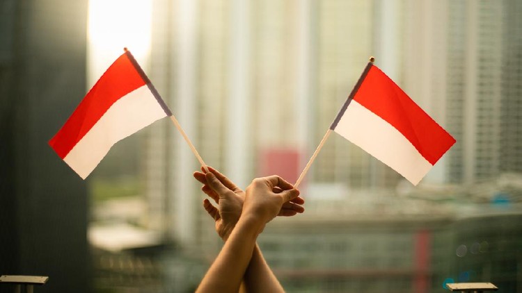 cropped hand of person holding Indonesia Flag in the city scape