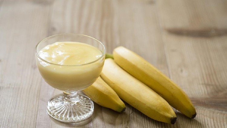 Banana pudding dessert in a glass cup on a wooden table.