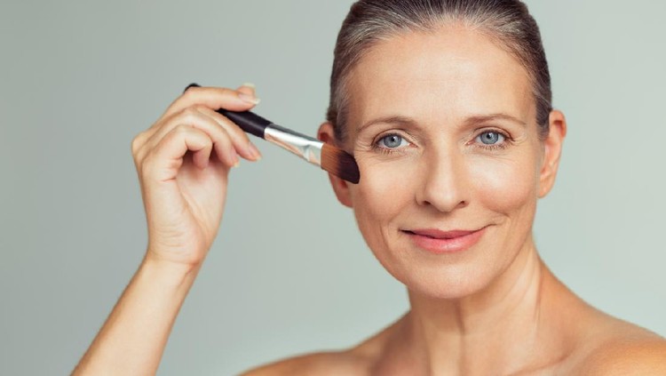 Ilustrasi Skincare Closeup portrait of mature woman applying tonal foundation on face with makeup brush. Smiling senior woman applying powder for make up. Cosmetics and make-up portrait.