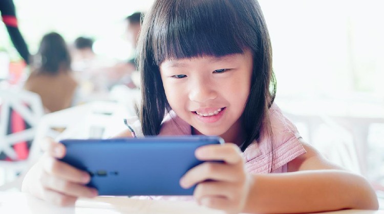 anak main gadget Asian girl watch video or play mobile game happily by cell phone