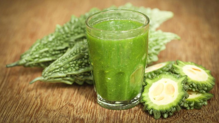 Herbal juice of green momodica in a glass with fresh vegetables