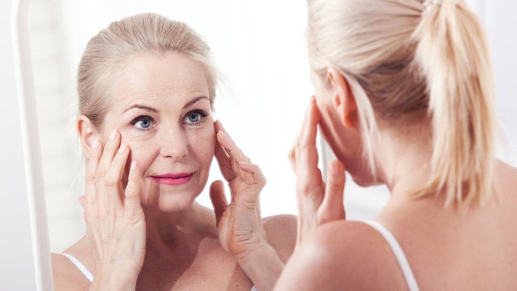 Middle aged woman looking at wrinkles in mirror. Plastic surgery and collagen injections. Makeup. Macro face. Selective focus on the face. Realistic images with their own imperfections.