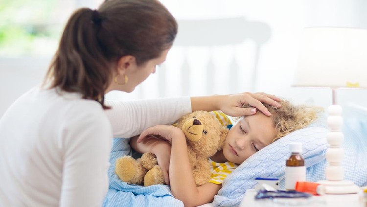 anak sakit Sick little boy with asthma medicine. Mother with ill child lying in bed. Unwell kid with chamber inhaler for cough treatment. Flu season. Parent in bedroom or hospital room for young patient.