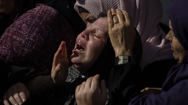 Satu ibu Palestina tersungkur di depan makam di Yerusalem, berupaya melindungi tempat peristirahatan terakhir anaknya yang dikabarkan bakal dibuldozer Israel.