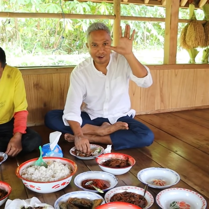 <p>Haji Usman Bimantara juga senang mengajak penduduk setempat untuk menikmati hidangan di gubuknya. Mereka menikmati makanan sederhana di tengah pemandangan sawah yang asri. (Foto: YouTube Petualangan Alam Desaku)</p>