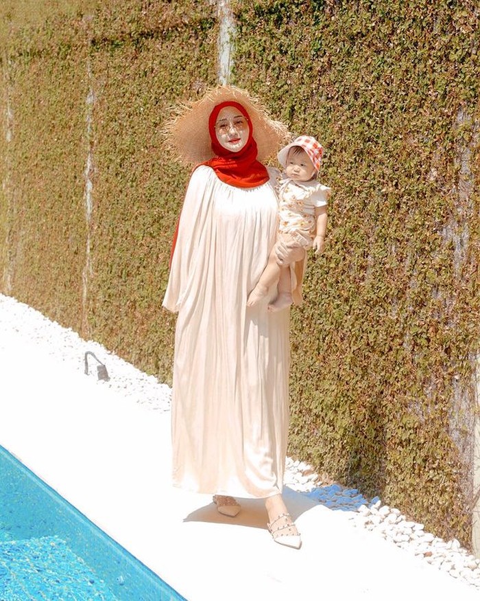 Walaupun sedang berada di rumah, Dian tampaknya sangat senang mengajak Rumi berfoto bersama. Kali ini berpose di pinggir kolam renang dengan mengenakan home dress dipadukan dengan hijab merah, lengkap dengan topi ala pantai. /Foto:@dianpelangi