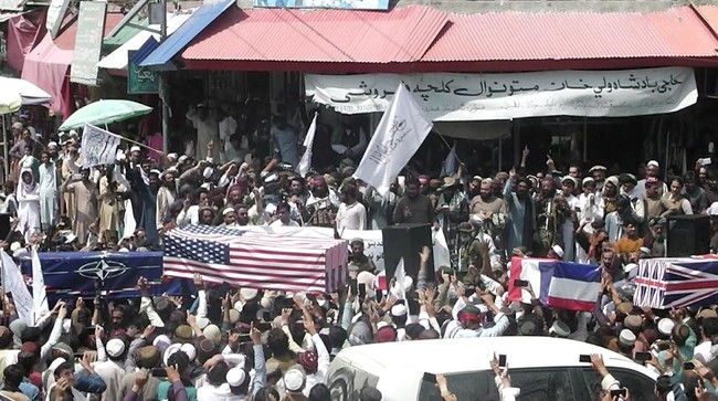 Pendukung Taliban di Kota Korst menggelar parade kemenangan dengan membawa peti mati yang diselimuti bendera Amerika Serikat dan negara asing lain.