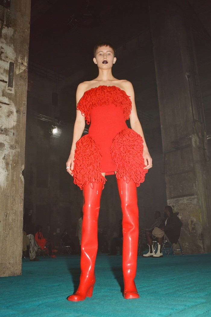 Sebuah strapless mini dress aksen knit peplum, tampil edgy dalam gaya serba merah dan padanan boots senada.Foto: Courtesy of Bottega Veneta