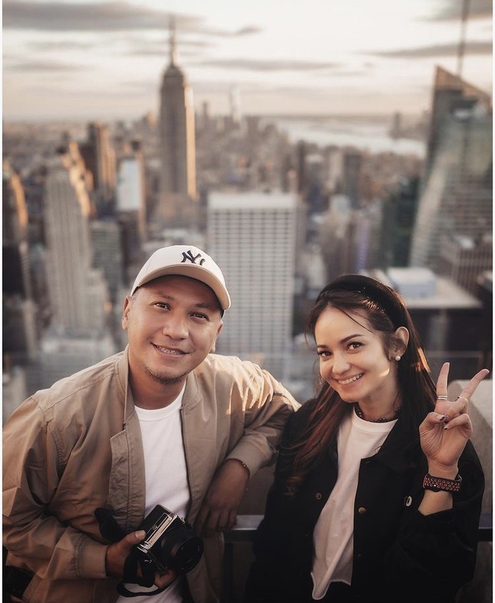Gading Marten dan Enzy Storia mengenakan T-shirt berwarna serupa dengan outer Erigo. Tone warna pakaian mereka selaras dengan latar kota Manhattan dikala golden hour yang memukau. Foto: instagram.com/gadiiing
