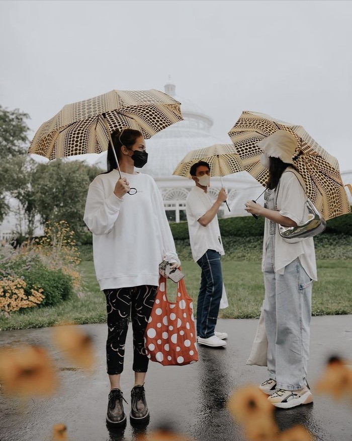 Masih mengenakan brand lokal Erigo, mereka juga menyempatkan berkunjung ke New York Botanical Garden. Enzy Storia, Febby Rastanty, dan Omar Daniel kompak mengenakan baju putih dan payung bermotif ciri khas Yayoi Kusama. Foto: instagram.com/enzystoria