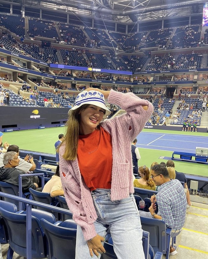 Selebriti lain yang turut berkolaborasi, Luna Maya, terlihat santai mengenakan T-shirt oranye Erigo dan cardigan pink. Bucket hat motif raket tenis menjadikan penampilannya semakin playful saat menyaksikan pertandingan US Open. Foto: instagram.com/lunamaya