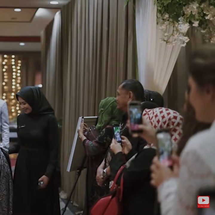 <p>Prosesi pernikahan dilanjutkan dengan acara resepsi. Mereka berganti pakaian dengan memakai baju adat bernuansa lebih gelap. Para tamu menyoroti mereka ketika memasuki ruangan. (Foto: YouTube Tess & Tom)</p>