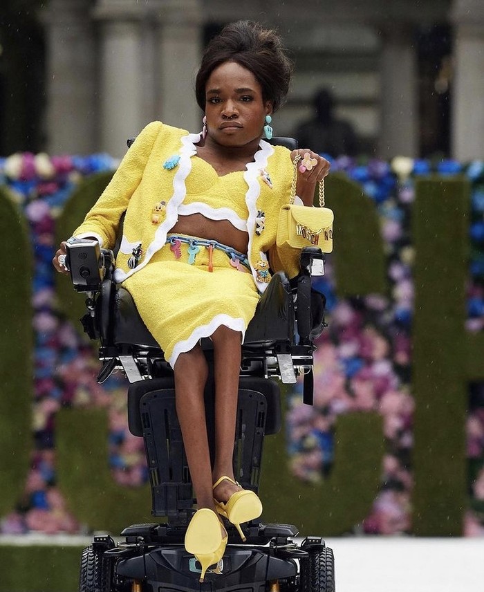 Spirit inklusif juga menjadi bagian dari fashion show Moschino ini di mana menunjuk seorang model transgender dan penyandang disabilitas untuk tampil. Aaron Rose Philip debut sebagai model Moschino musim ini dengan mengenakan setelan dan tas mini. Keren bukan? Foto: instagram.com/ellethailandofficial