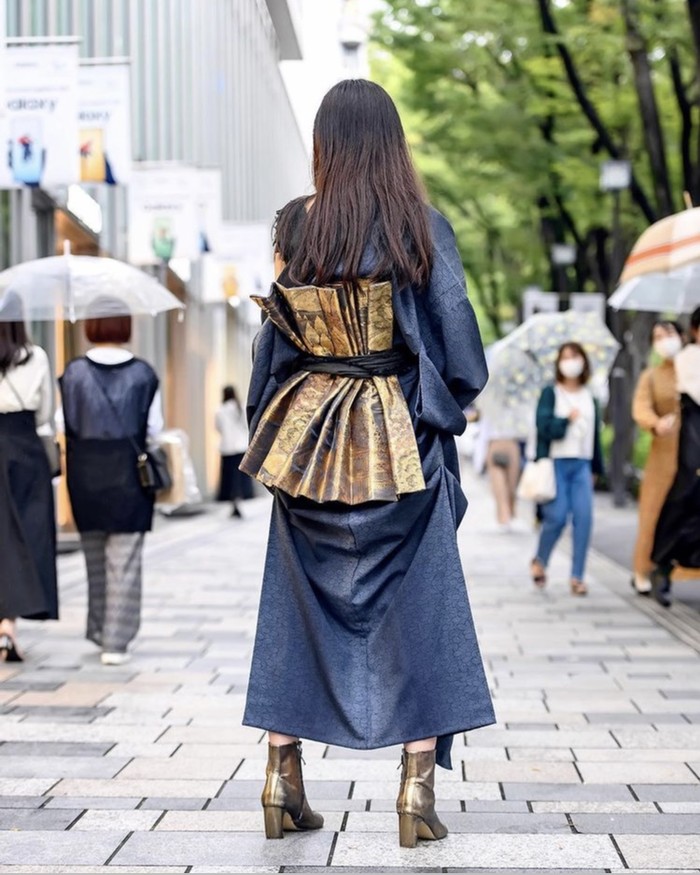 Pakaian tradisional Jepang, kimono, tampak lebih modern dengan modifikasi one shoulder dan obi belt berdekorasi emas metalik di bagian belakang. Permainan warna metalik dan denim membuat kesatuan look yang dinamis. Foto: instagram.com/tokyofashion