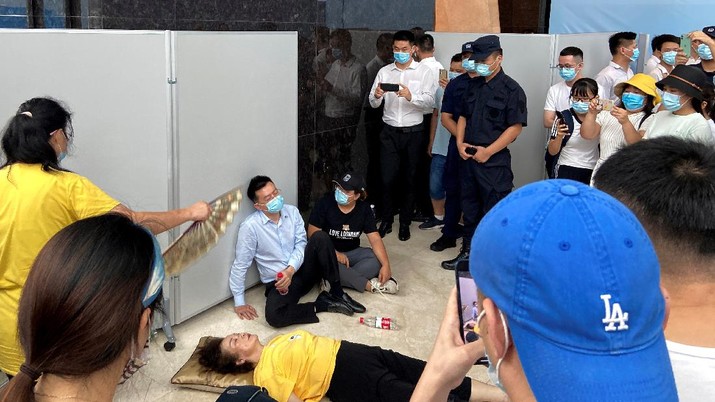 A woman receives aid on the ground next to Du Liang, general manager and legal representative of Evergrande's wealth management division, while people gather to demand repayment of loans and financial products at the Evergrande's headquarters, in Shenzhen, Guangdong province, China September 13, 2021. REUTERS/David Kirton REFILE- CORRECTING NAME
