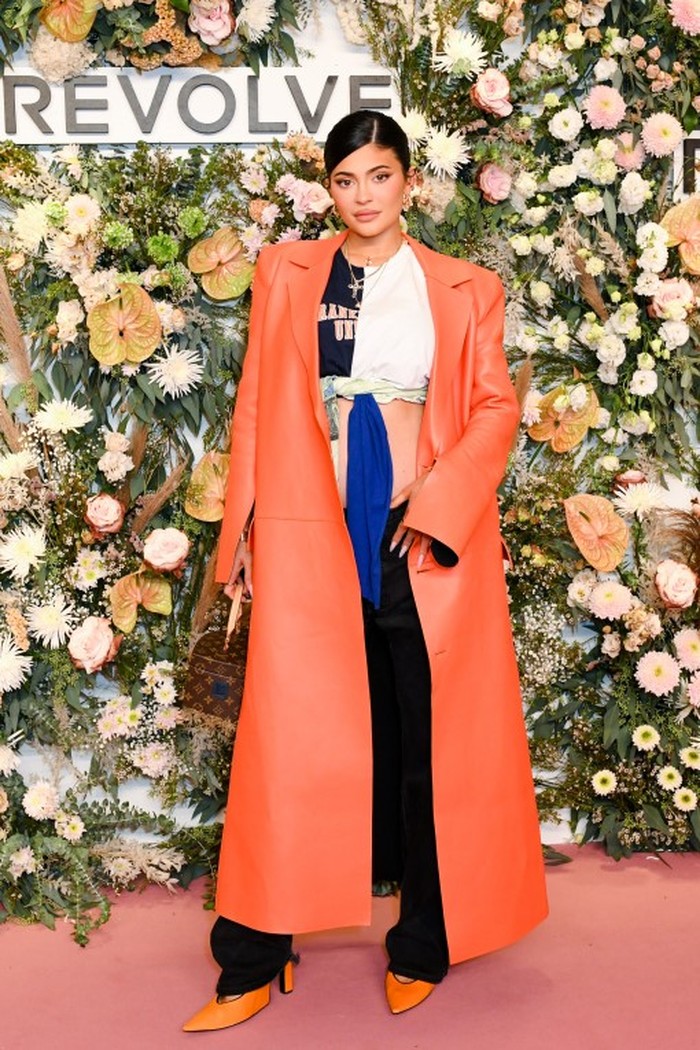 Untuk Kylie Jenner yang sedang mengandung anak keduanya, dia tampak memilih mengenakan coat orange panjang. Namun, ia memilih memadukan dengan crop top putih dan juga celana panjang hitam. /Foto: bfa.com/Joe