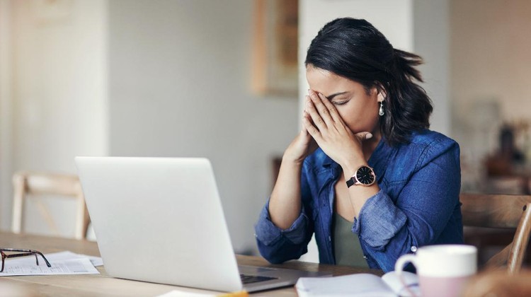 Shot of a young woman looking stressed while using a laptop to work from home