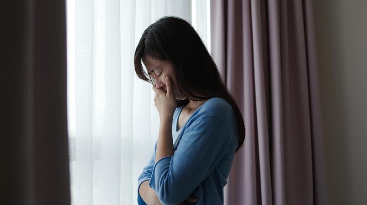 Foto ilustrasi wanita yang mengalami ghosting. asian depression sad woman is standing by windows alone at home and thinking negative thoughts
