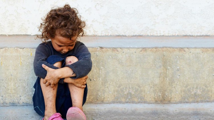 154216694 poor, sad little child girl sitting against the concrete wall