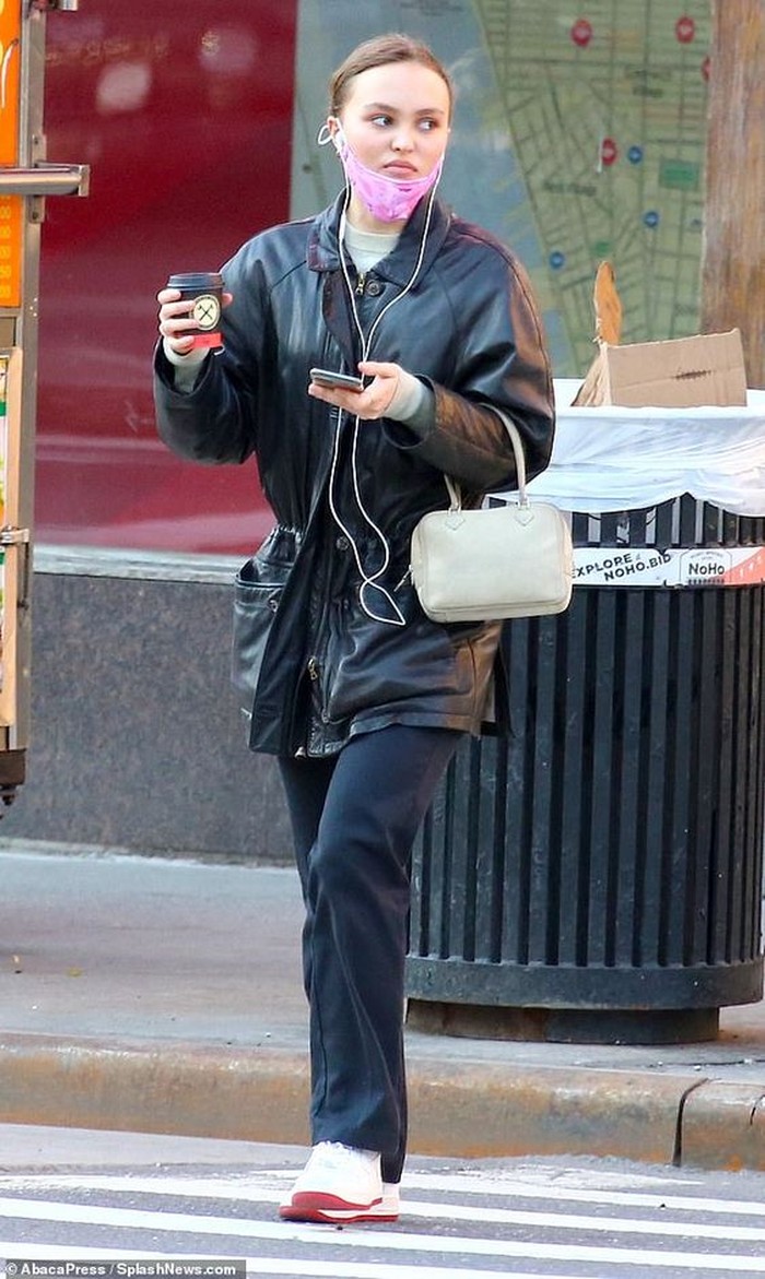 Memakai pakaian yang serba hitam, Lily Rose Depp terlihat sendirian di jalan sambil memegang segelas kopi dan membawa tas cantik berwarna putih/foto: id.pinterest.com/Daily Mail