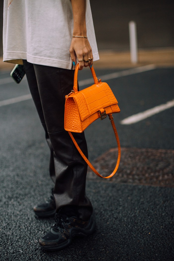 Pilihan tas dalam warna orange memberi nuansa quirky pada tampilan monokrom. Foto: livingly.com/IMAXtree