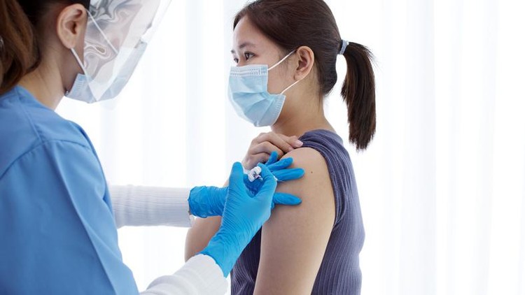 Practitioner vaccinating woman patient in clinic. Doctor giving injection to adult woman at hospital. Nurse holding syringe and inject Covid-19 or coronavirus vaccine.Injection covid vaccine concept.